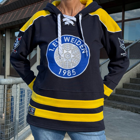 Person trägt einen dunkelblauen Kapuzenpullover mit gelben Akzenten und dem Logo des Eishockeyvereins 1. EV Weiden (gegründet 1985) auf der Brust.